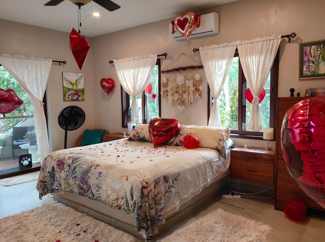 A bedroom with a bed, dresser and fan.