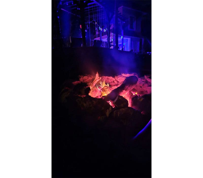 A fire burning in the dark with purple lighting.