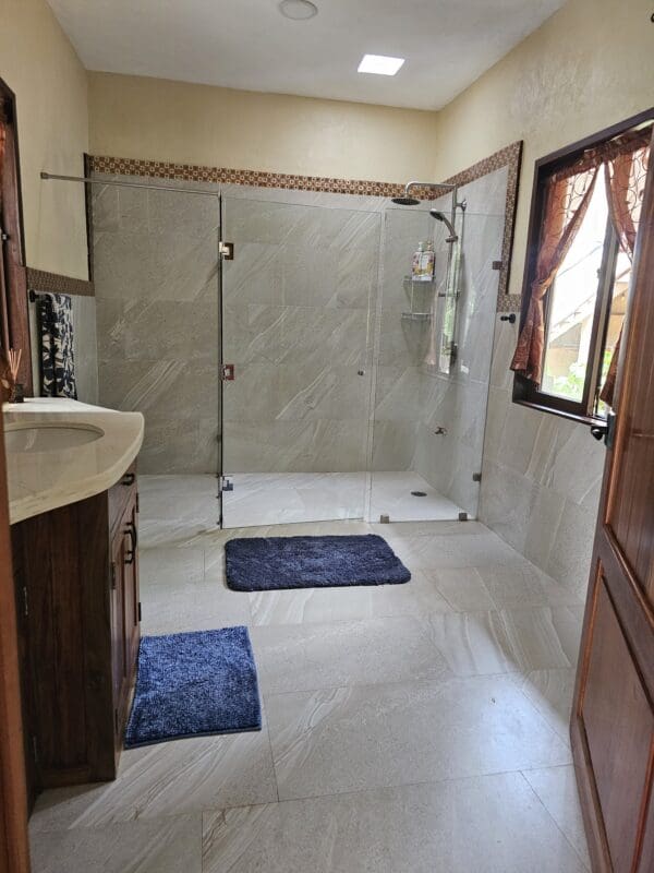 A bathroom with two sinks and a walk in shower.