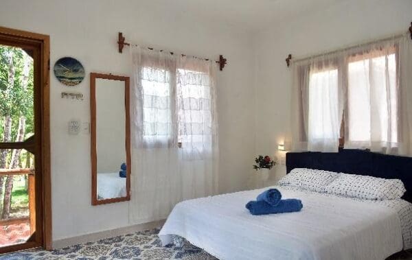 A bedroom with a bed, mirror and window.