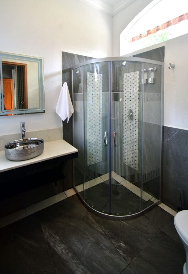 A bathroom with a sink, mirror and shower.