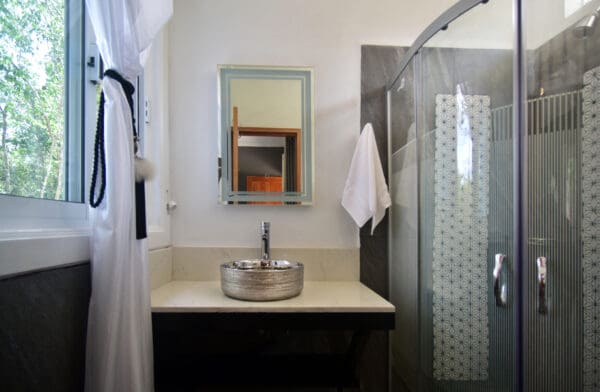 A bathroom with a sink, mirror and shower.