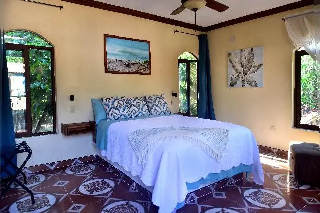 A bedroom with a bed, ceiling fan and window.