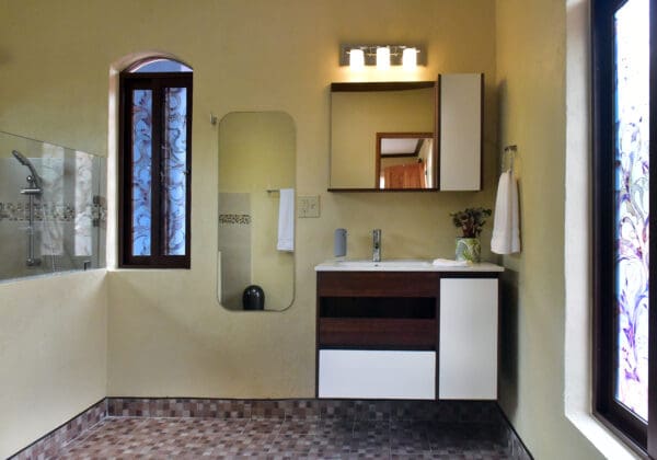 A bathroom with a sink, mirror and window.