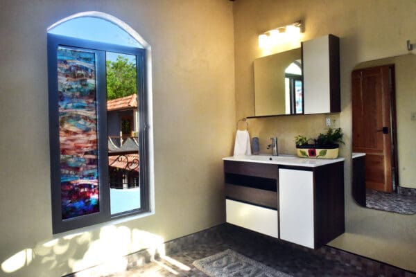 A bathroom with a sink, mirror and window.