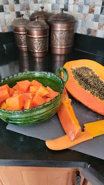 A bowl of cut up fruit next to a piece of papaya.