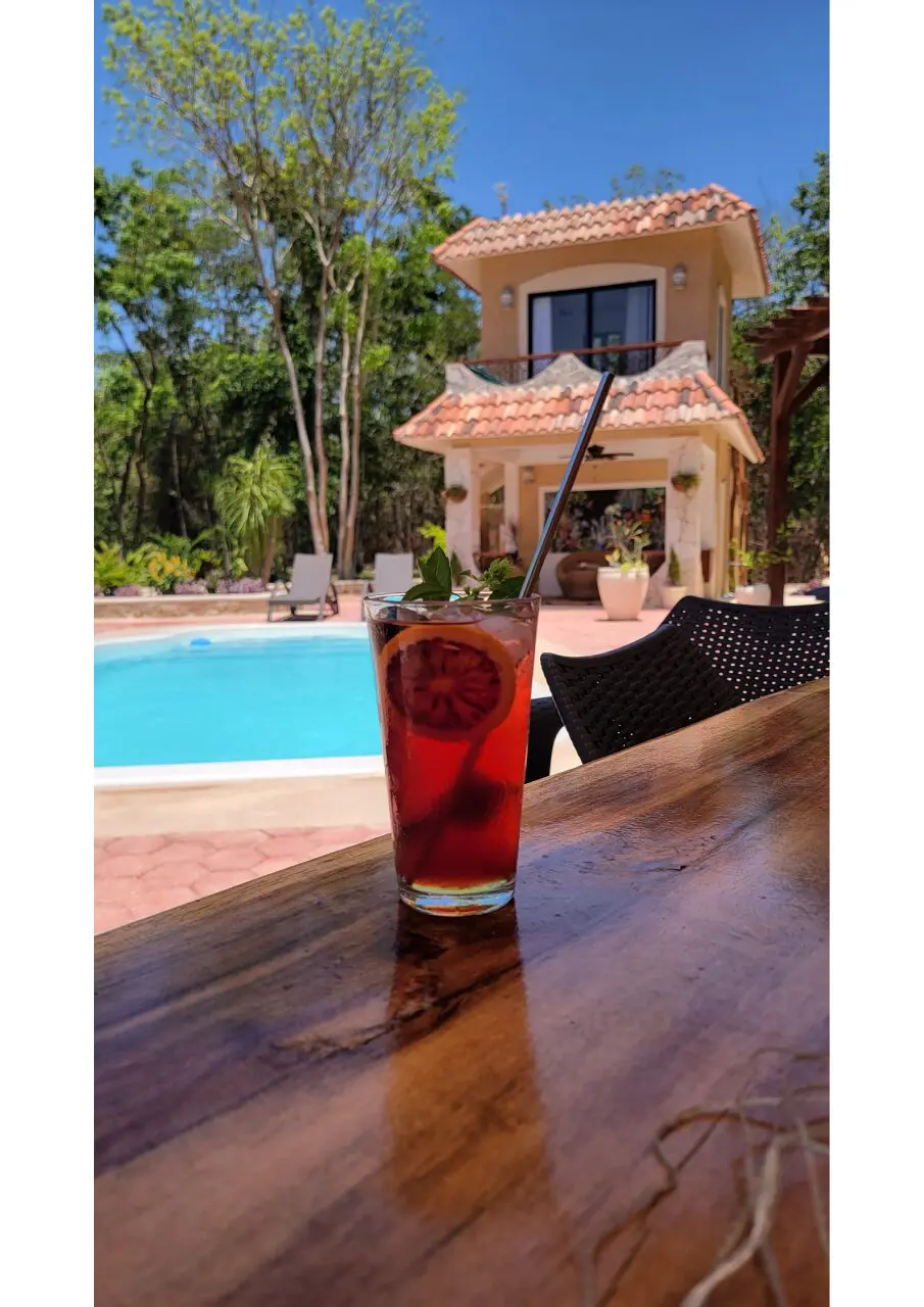 A glass of red liquid on the table near a pool.