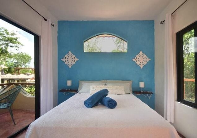 A bed room with a blue wall and white sheets