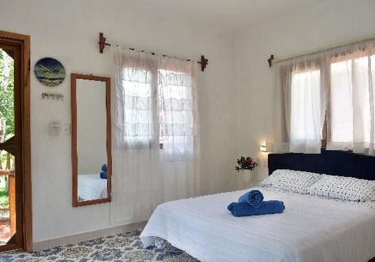 A bedroom with a bed, mirror and window.