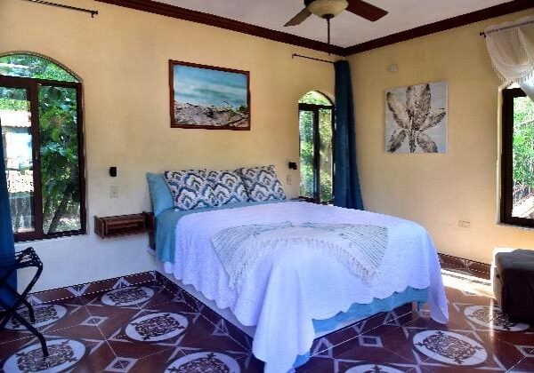 A bedroom with a bed, ceiling fan and window.