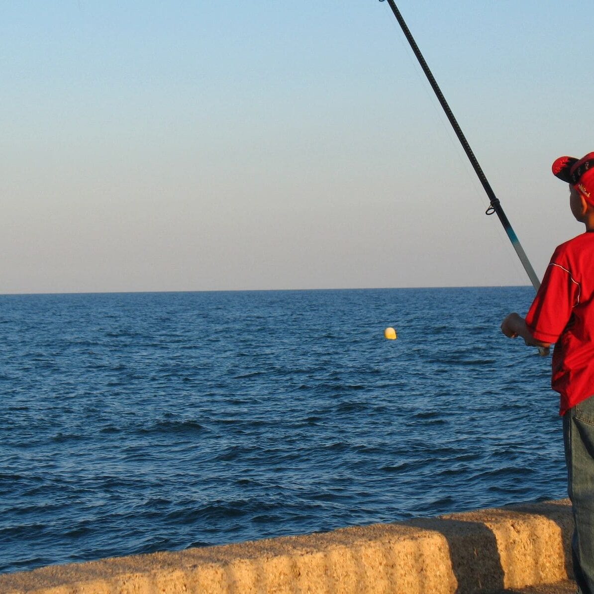 A man fishing on the beach with an ocean in background.